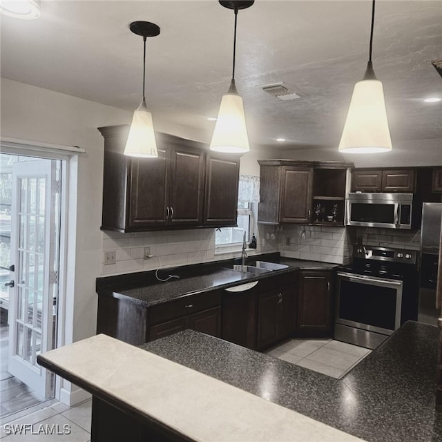 kitchen with appliances with stainless steel finishes, hanging light fixtures, and tasteful backsplash