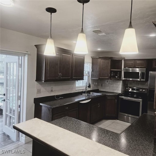 kitchen featuring stainless steel appliances, a sink, dark brown cabinetry, and decorative backsplash