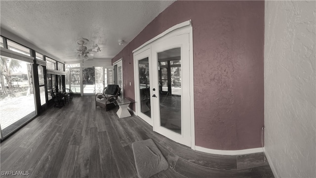 hallway with french doors, a textured ceiling, and dark hardwood / wood-style floors