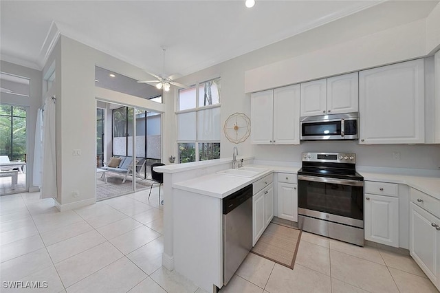 kitchen featuring light tile patterned floors, white cabinets, a peninsula, stainless steel appliances, and a sink