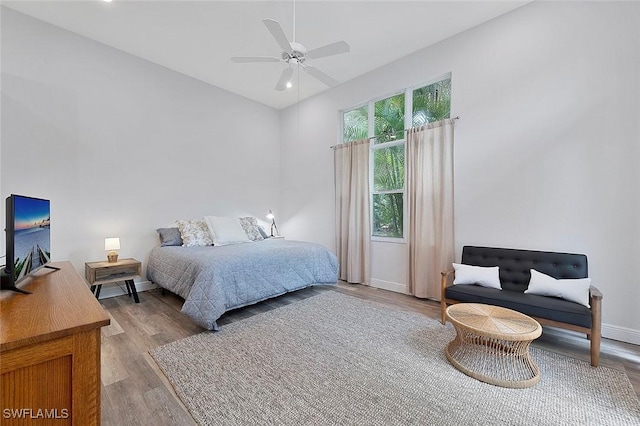 bedroom with ceiling fan, light wood-type flooring, and baseboards