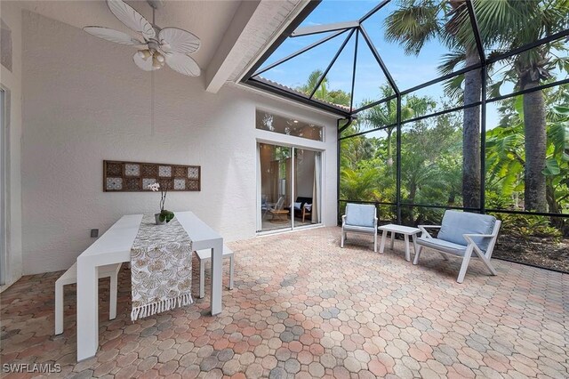 unfurnished sunroom featuring ceiling fan, beamed ceiling, and a healthy amount of sunlight