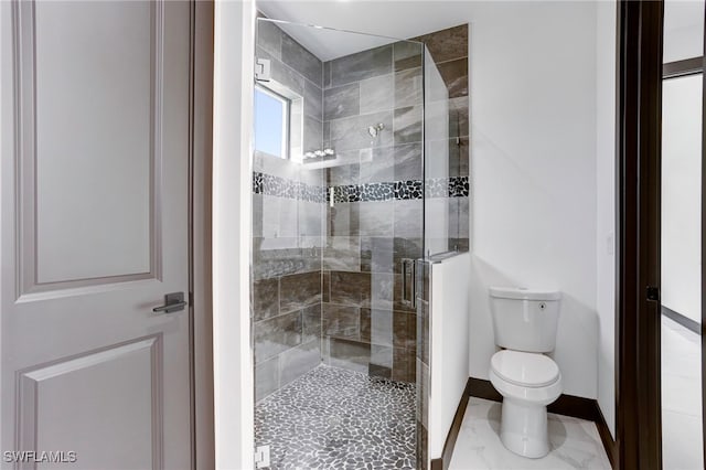 bathroom with a stall shower, toilet, and baseboards