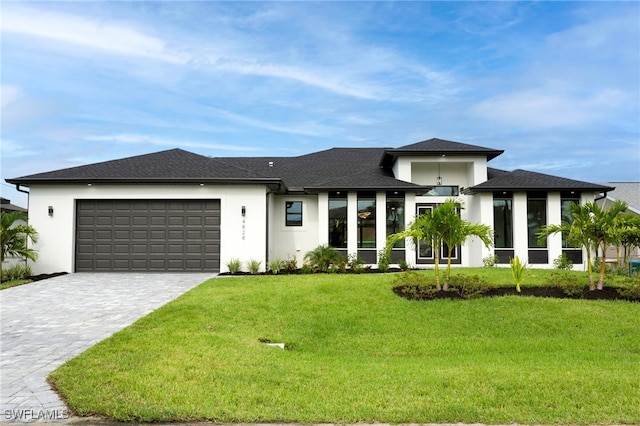 prairie-style house with decorative driveway, an attached garage, stucco siding, and a front yard