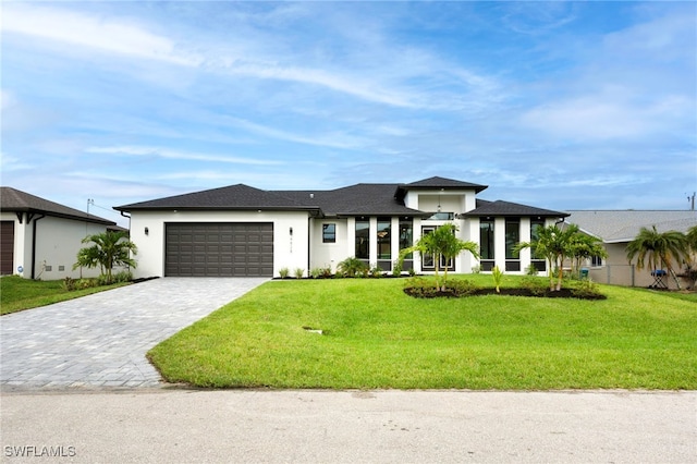 prairie-style house featuring a garage, a front lawn, decorative driveway, and stucco siding