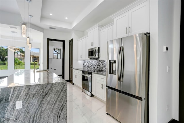 kitchen with decorative backsplash, appliances with stainless steel finishes, marble finish floor, a tray ceiling, and a sink