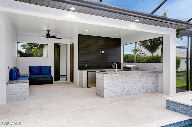 view of patio with area for grilling, a ceiling fan, a sink, outdoor wet bar, and a lanai