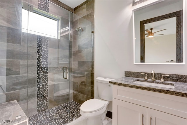 bathroom featuring vanity, a shower with shower door, ceiling fan, and toilet