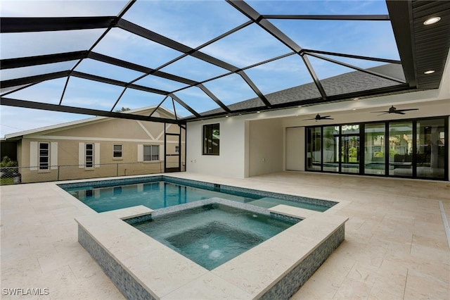 view of pool with a patio, glass enclosure, a pool with connected hot tub, and a ceiling fan