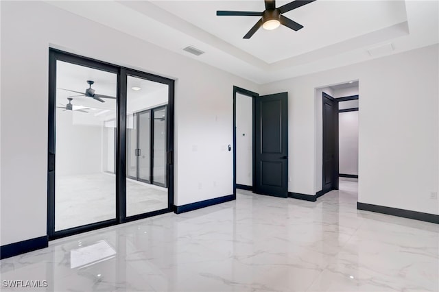 empty room featuring a tray ceiling, marble finish floor, visible vents, ceiling fan, and baseboards