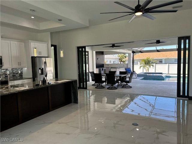 kitchen featuring white cabinetry, decorative backsplash, dark stone counters, ceiling fan, and stainless steel appliances