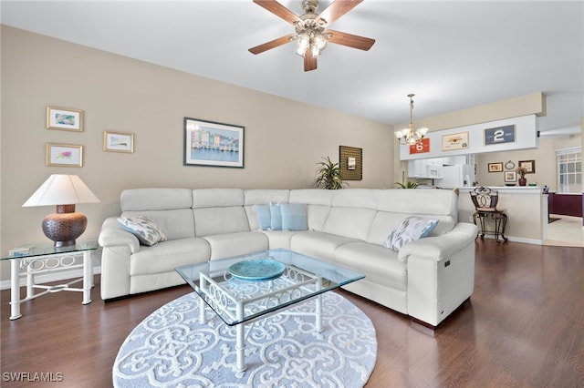 living room with ceiling fan with notable chandelier and dark hardwood / wood-style floors