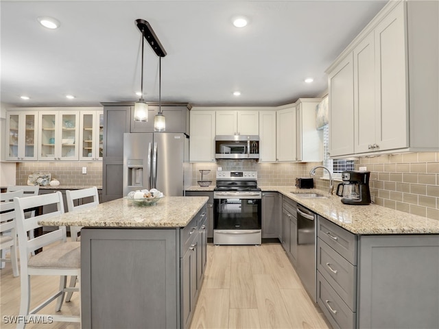 kitchen featuring hanging light fixtures, sink, a kitchen island, gray cabinetry, and appliances with stainless steel finishes