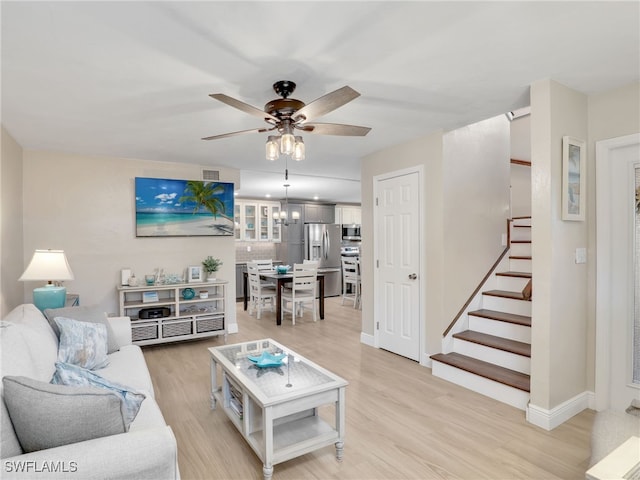 living room featuring ceiling fan with notable chandelier and light hardwood / wood-style floors