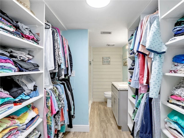 walk in closet with light hardwood / wood-style flooring