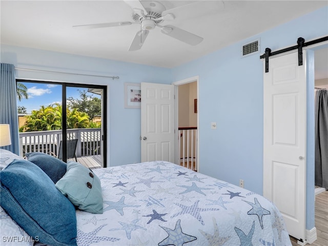 bedroom with ceiling fan, a barn door, access to exterior, and wood-type flooring