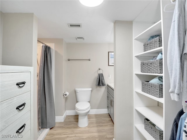 bathroom featuring walk in shower, vanity, hardwood / wood-style floors, and toilet