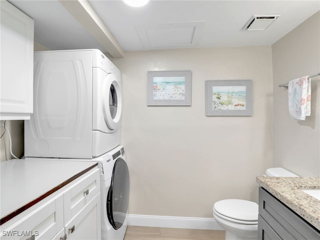 laundry area with light wood-type flooring and stacked washer and clothes dryer