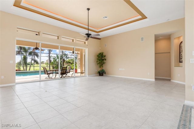 tiled empty room with a tray ceiling and ceiling fan