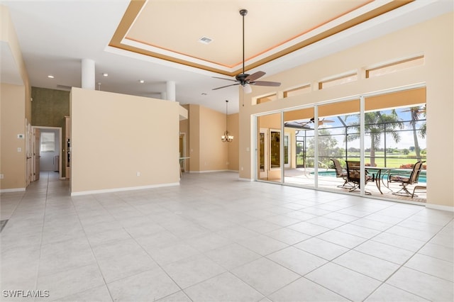 unfurnished room with ceiling fan with notable chandelier, a tray ceiling, a high ceiling, and light tile patterned floors