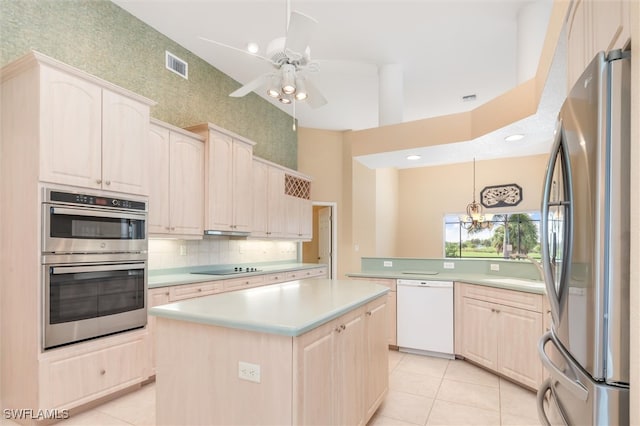 kitchen with ceiling fan, a kitchen island, tasteful backsplash, a towering ceiling, and appliances with stainless steel finishes