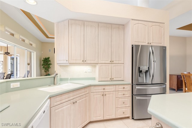 kitchen with sink, decorative backsplash, white dishwasher, light tile patterned floors, and stainless steel fridge