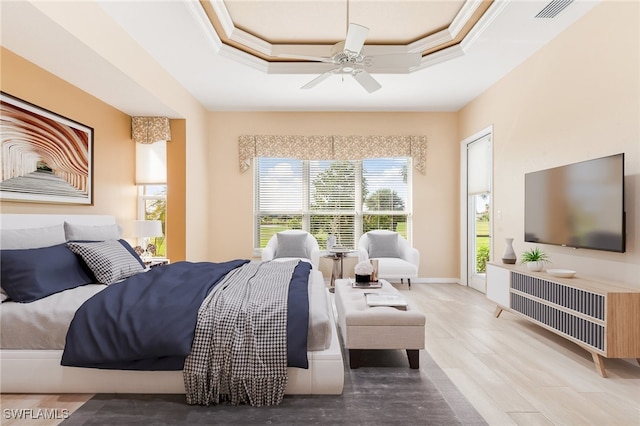 bedroom featuring ceiling fan, crown molding, hardwood / wood-style flooring, and a tray ceiling