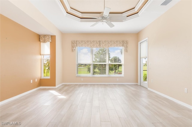 empty room with light hardwood / wood-style floors, ceiling fan, a raised ceiling, and ornamental molding