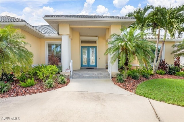 property entrance with stucco siding, a tiled roof, and french doors