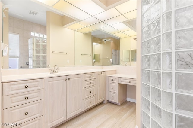 bathroom featuring a paneled ceiling, hardwood / wood-style flooring, a shower, vanity, and ceiling fan