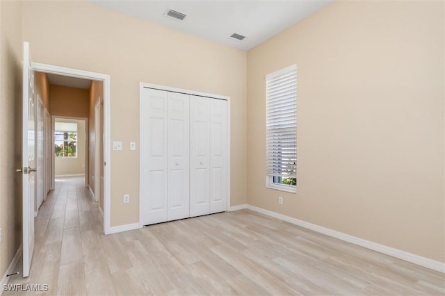 unfurnished bedroom with visible vents, multiple windows, light wood-style flooring, and baseboards