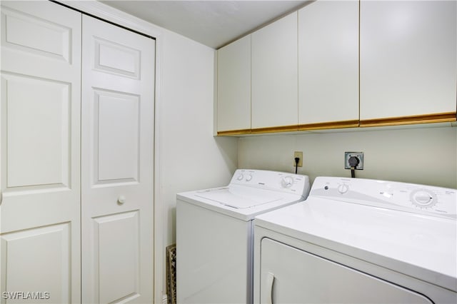 laundry area with independent washer and dryer and cabinets