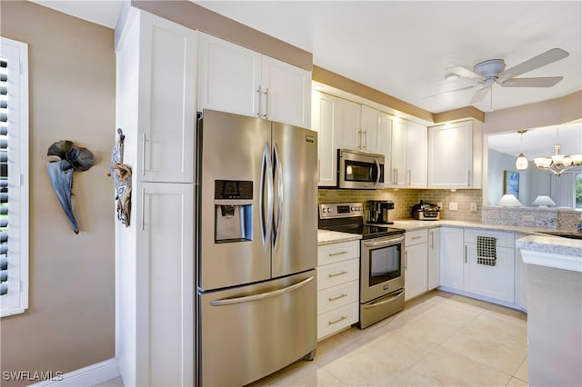 kitchen with ceiling fan with notable chandelier, appliances with stainless steel finishes, tasteful backsplash, white cabinets, and light tile patterned flooring