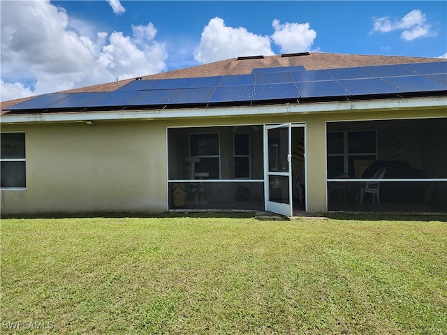 rear view of house featuring solar panels, a sunroom, and a lawn