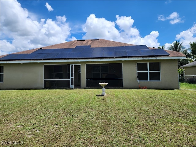 rear view of property featuring solar panels, a sunroom, and a yard