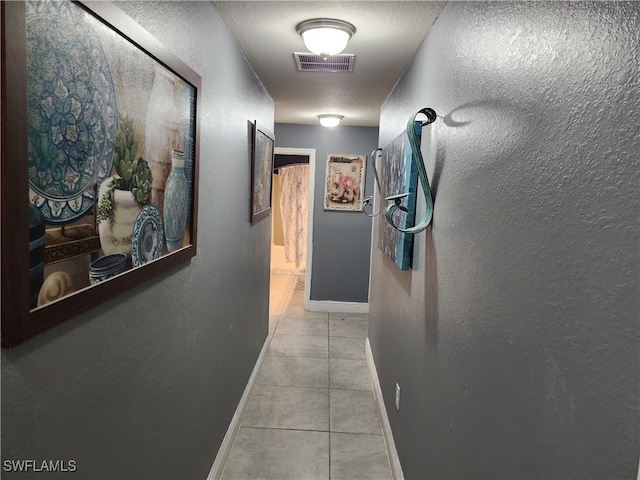 corridor with a textured ceiling and light tile patterned flooring