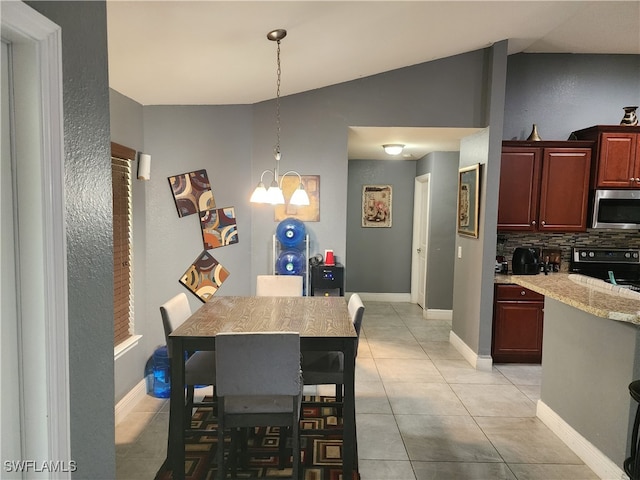 tiled dining room featuring vaulted ceiling and an inviting chandelier