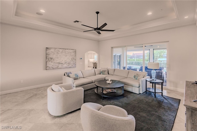 tiled living room with a tray ceiling and ceiling fan