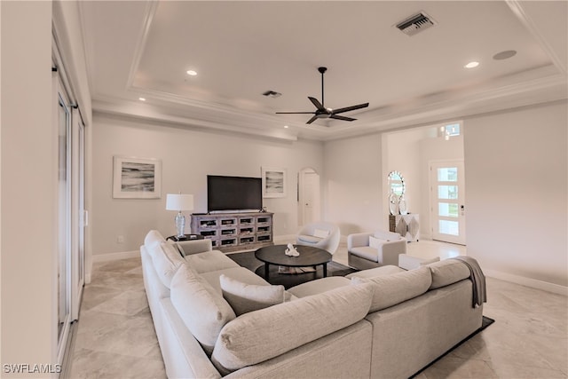 living room with ceiling fan, a tray ceiling, and light tile patterned flooring