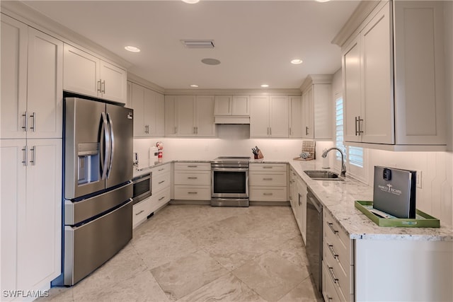 kitchen featuring light tile patterned floors, light stone countertops, stainless steel appliances, white cabinetry, and sink