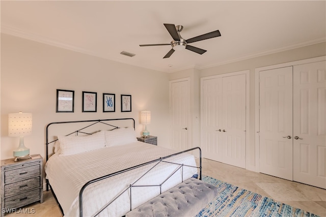 tiled bedroom featuring crown molding, ceiling fan, and multiple closets