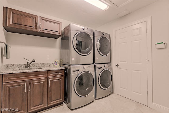 laundry room with light tile patterned flooring, cabinets, stacked washer / drying machine, and sink