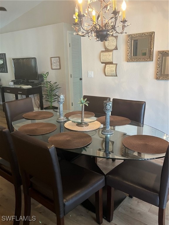 dining room with vaulted ceiling, a notable chandelier, and hardwood / wood-style flooring