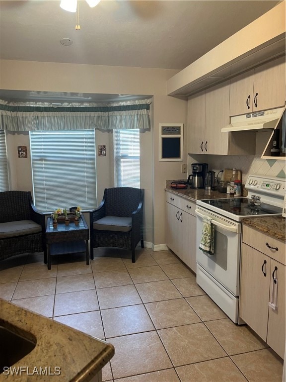 kitchen featuring light tile patterned flooring, white range with electric stovetop, backsplash, and light brown cabinets