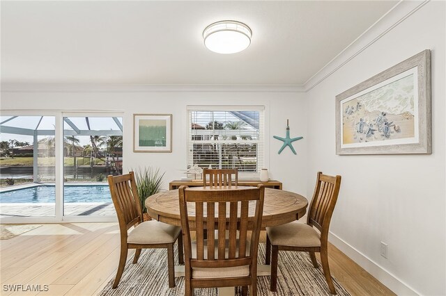 dining space with light hardwood / wood-style floors and ornamental molding