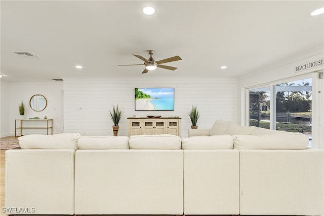 living room featuring ceiling fan, light wood-type flooring, and crown molding