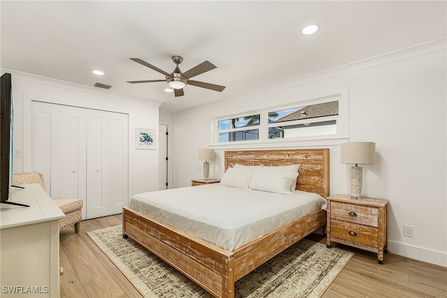 bedroom featuring ceiling fan, a closet, light hardwood / wood-style floors, and ornamental molding