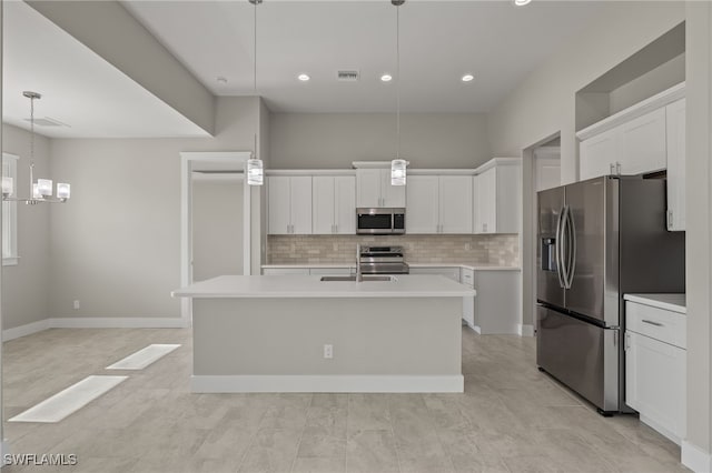 kitchen with tasteful backsplash, a kitchen island with sink, white cabinetry, appliances with stainless steel finishes, and decorative light fixtures