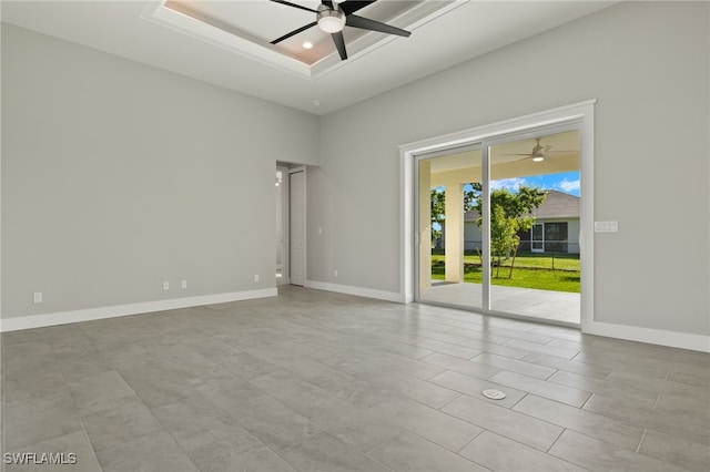 tiled spare room featuring ceiling fan, a tray ceiling, and a high ceiling