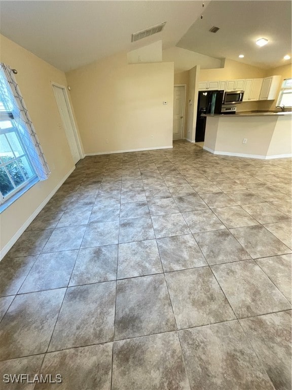 unfurnished living room featuring vaulted ceiling and light tile patterned flooring